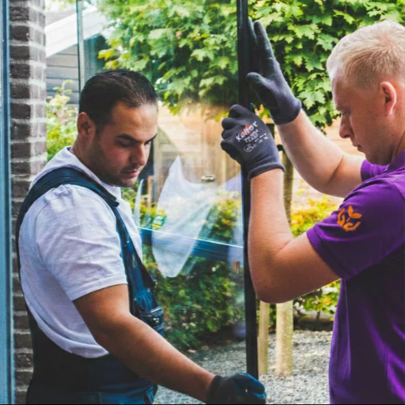 Twee glaszetters plaatsen isolerend glas in een woning