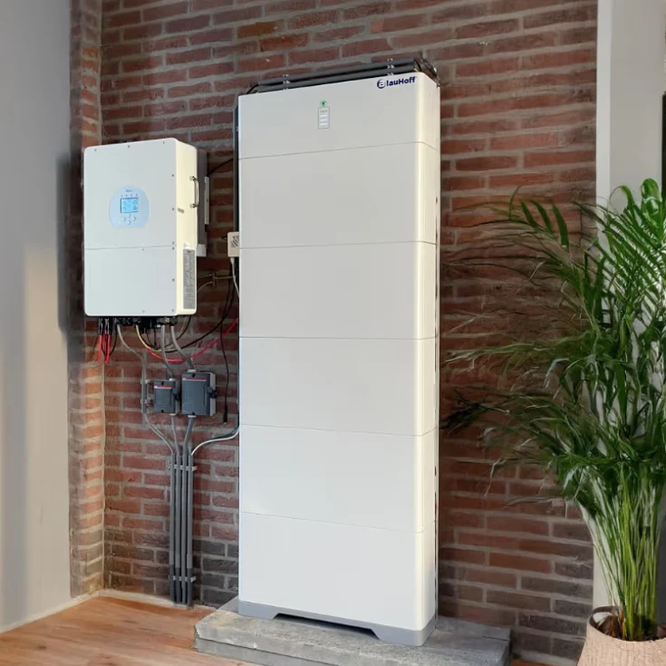 Thuisbatterij en omvormer gemonteerd aan een bakstenen muur