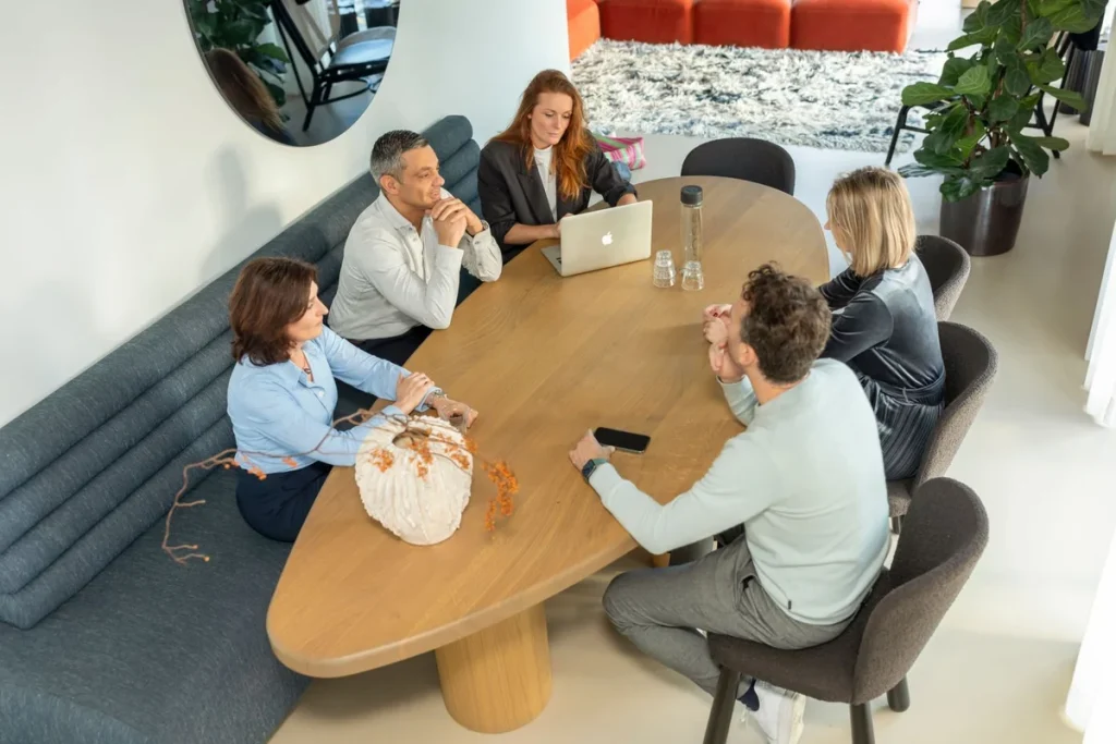 Groep mensen in gesprek rond een tafel tijdens een adviesgesprek