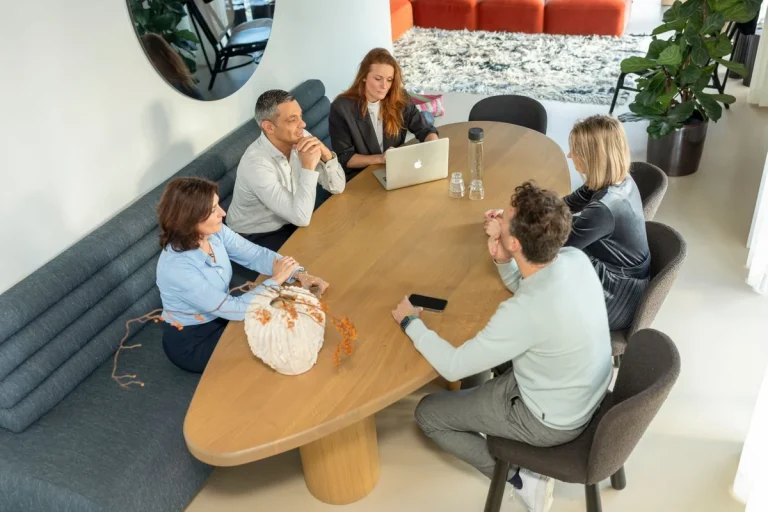 Groep mensen in gesprek rond een tafel tijdens een adviesgesprek